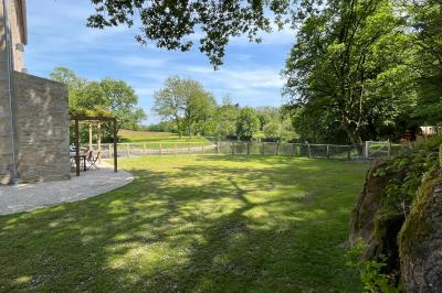 Groupe de personnes rassemblées sur une terrasse en bord de rivière, entourée de verdure et décorée de guirlandes lumineuses.