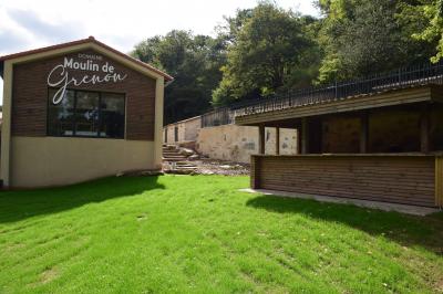 Groupe de personnes rassemblées sur une terrasse en bord de rivière, entourée de verdure et décorée de guirlandes lumineuses.