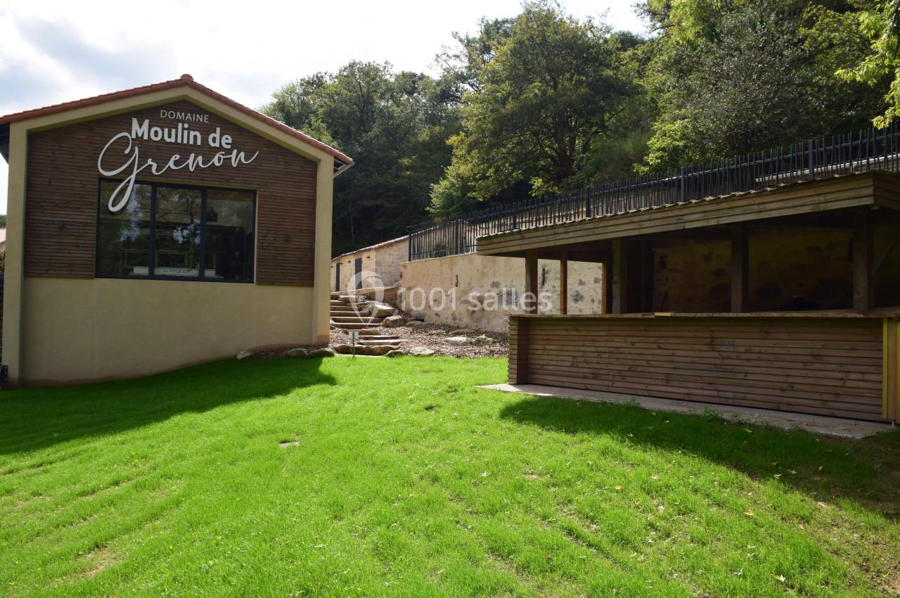 Bâtiment moderne avec une enseigne ’Domaine Moulin de Grenon’, terrasse en bois et espace vert environnant.