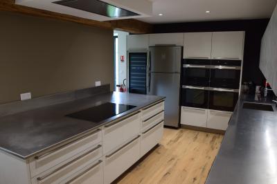 Groupe de personnes rassemblées sur une terrasse en bord de rivière, entourée de verdure et décorée de guirlandes lumineuses.