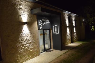 Groupe de personnes rassemblées sur une terrasse en bord de rivière, entourée de verdure et décorée de guirlandes lumineuses.