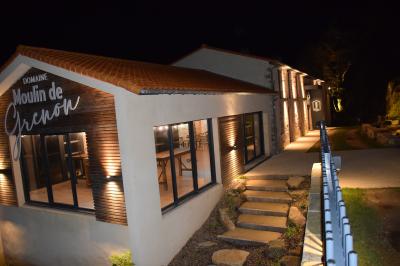 Groupe de personnes rassemblées sur une terrasse en bord de rivière, entourée de verdure et décorée de guirlandes lumineuses.