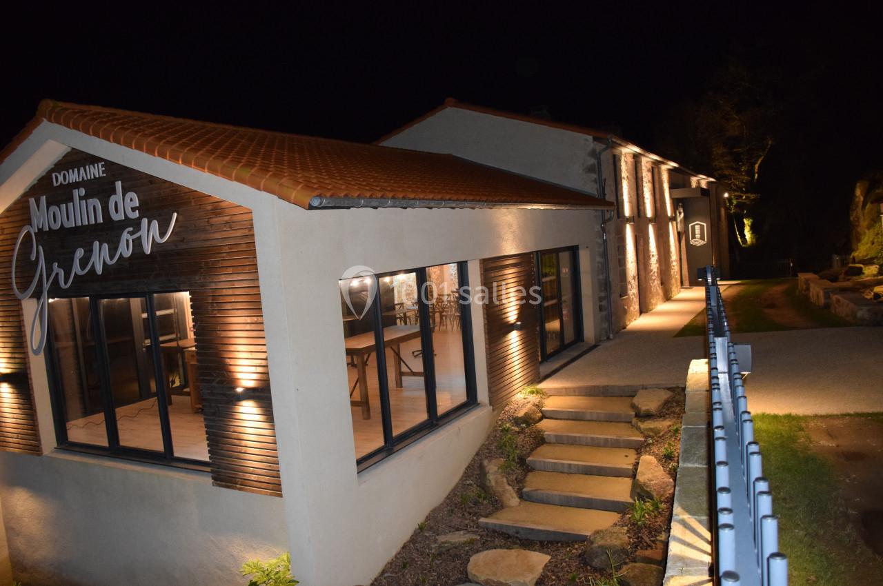 Bâtiment moderne éclairé de nuit avec inscription ’Domaine Moulin de Grenon’ sur la façade.