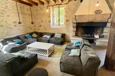 Groupe de personnes rassemblées sur une terrasse en bord de rivière, entourée de verdure et décorée de guirlandes lumineuses.