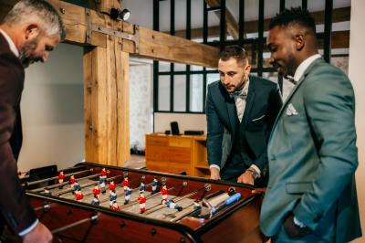 Groupe de personnes rassemblées sur une terrasse en bord de rivière, entourée de verdure et décorée de guirlandes lumineuses.