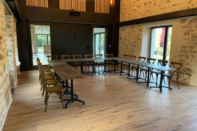 Groupe de personnes rassemblées sur une terrasse en bord de rivière, entourée de verdure et décorée de guirlandes lumineuses.