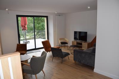 Groupe de personnes rassemblées sur une terrasse en bord de rivière, entourée de verdure et décorée de guirlandes lumineuses.