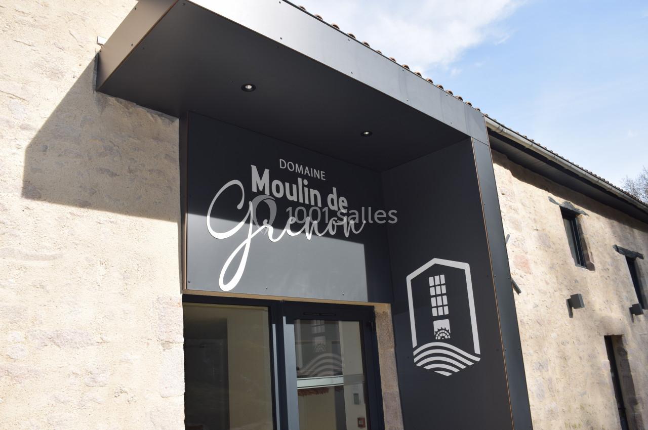 Entrée d'un bâtiment en pierre avec une enseigne indiquant ’Domaine Moulin de Grenon’ et un logo stylisé.