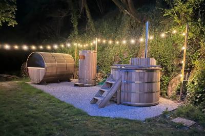 Groupe de personnes rassemblées sur une terrasse en bord de rivière, entourée de verdure et décorée de guirlandes lumineuses.
