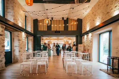 Groupe de personnes rassemblées sur une terrasse en bord de rivière, entourée de verdure et décorée de guirlandes lumineuses.