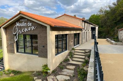 Groupe de personnes rassemblées sur une terrasse en bord de rivière, entourée de verdure et décorée de guirlandes lumineuses.
