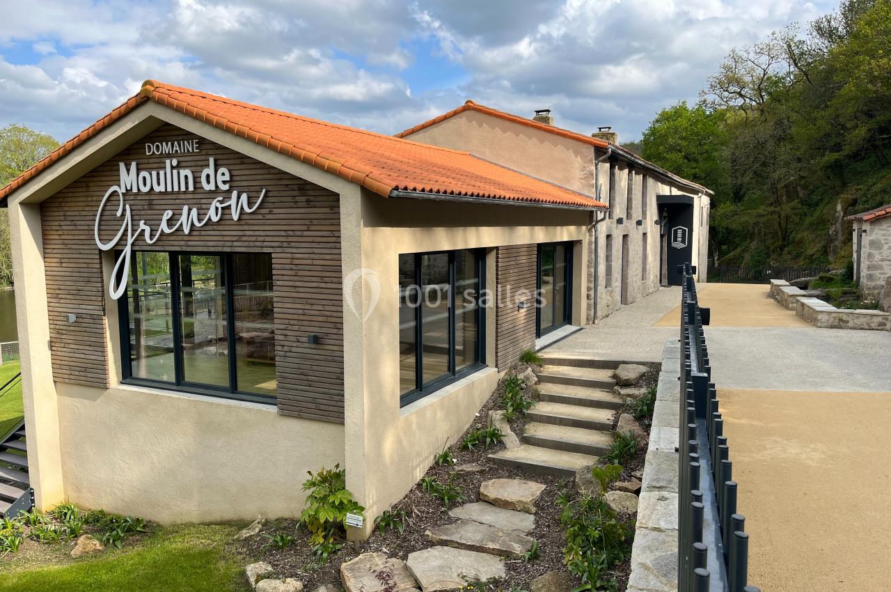 Bâtiment moderne avec façade en bois et toit en tuiles, entouré de verdure et d'un chemin pavé.