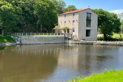 Groupe de personnes rassemblées sur une terrasse en bord de rivière, entourée de verdure et décorée de guirlandes lumineuses.