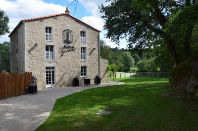 Groupe de personnes rassemblées sur une terrasse en bord de rivière, entourée de verdure et décorée de guirlandes lumineuses.