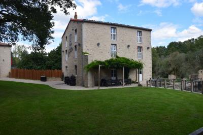 Groupe de personnes rassemblées sur une terrasse en bord de rivière, entourée de verdure et décorée de guirlandes lumineuses.