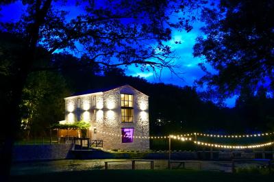 Groupe de personnes rassemblées sur une terrasse en bord de rivière, entourée de verdure et décorée de guirlandes lumineuses.