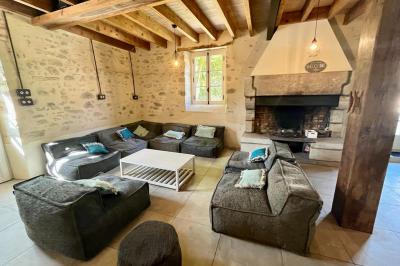 Groupe de personnes rassemblées sur une terrasse en bord de rivière, entourée de verdure et décorée de guirlandes lumineuses.