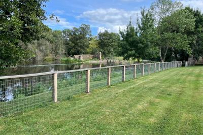 Groupe de personnes rassemblées sur une terrasse en bord de rivière, entourée de verdure et décorée de guirlandes lumineuses.