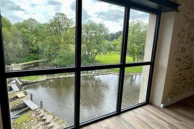 Groupe de personnes rassemblées sur une terrasse en bord de rivière, entourée de verdure et décorée de guirlandes lumineuses.