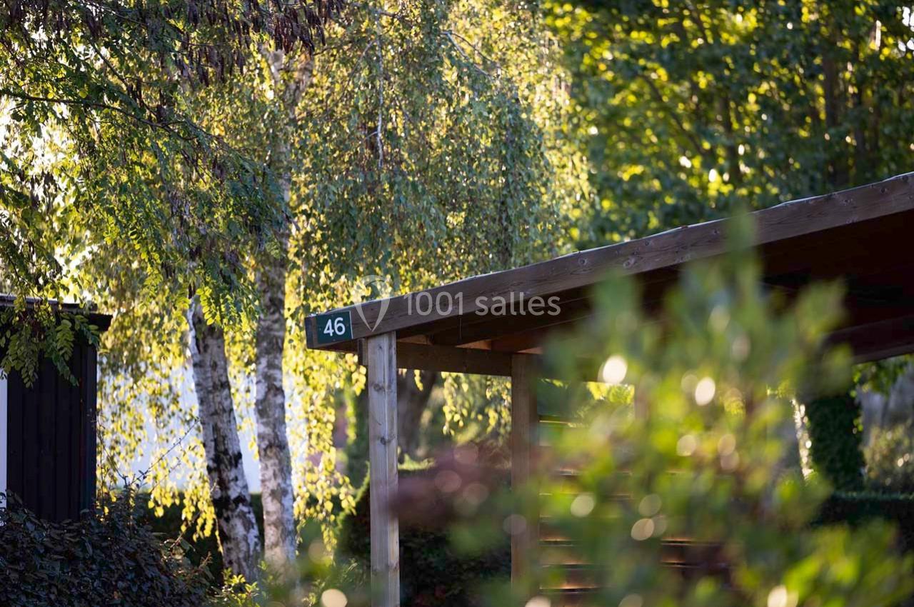 Abri en bois avec le numéro 46, entouré d'arbres et de feuillage sous une lumière naturelle.