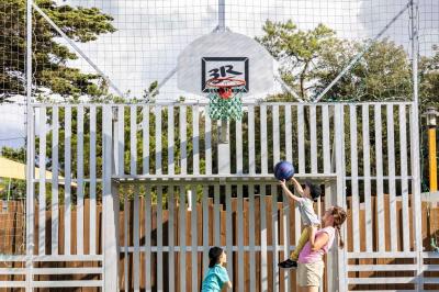 Table en bois avec assiettes d'huîtres, verres de vin blanc, citron et bouteille, dans un jardin ensoleillé avec fauteuil.