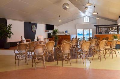 Table en bois avec assiettes d'huîtres, verres de vin blanc, citron et bouteille, dans un jardin ensoleillé avec fauteuil.