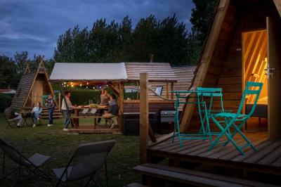 Table en bois avec assiettes d'huîtres, verres de vin blanc, citron et bouteille, dans un jardin ensoleillé avec fauteuil.