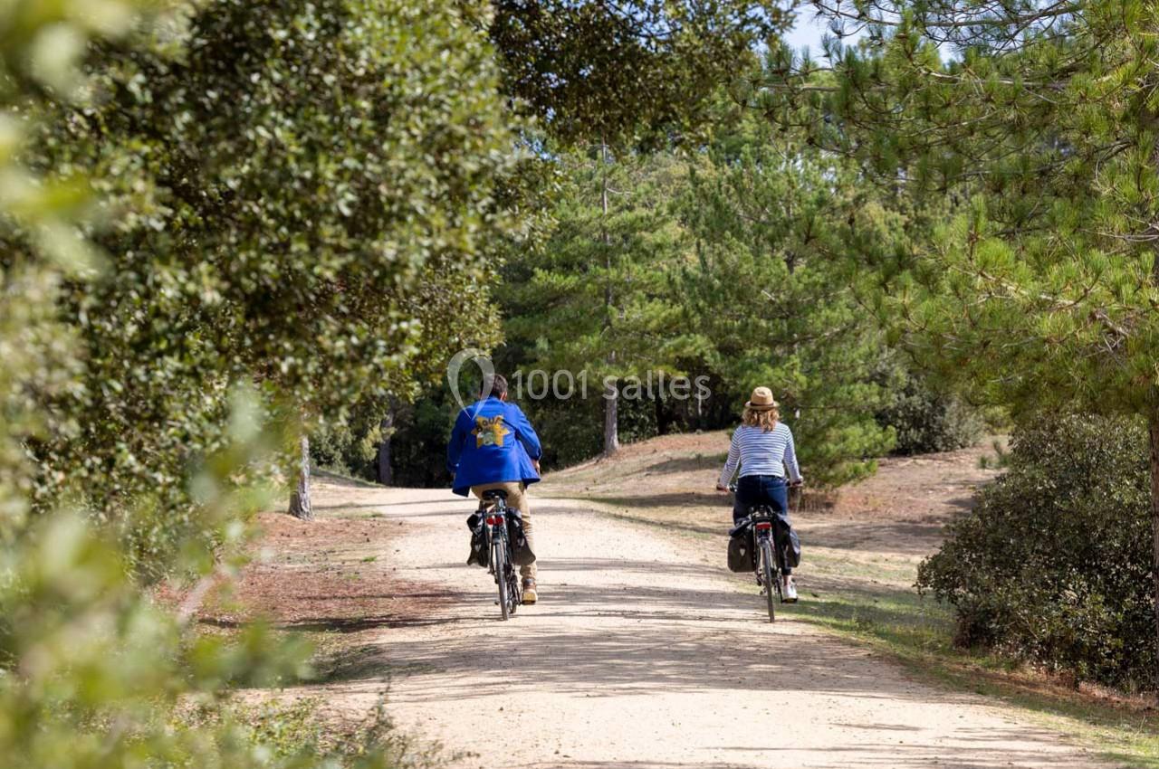Deux personnes à vélo sur un chemin forestier bordé d'arbres et de végétation.