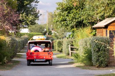 Salle de bain lumineuse avec douche vitrée, lavabo blanc, miroir, et accessoires de toilette.