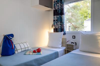 Salle de bain lumineuse avec douche vitrée, lavabo blanc, miroir, et accessoires de toilette.