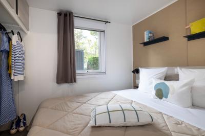 Salle de bain lumineuse avec douche vitrée, lavabo blanc, miroir, et accessoires de toilette.