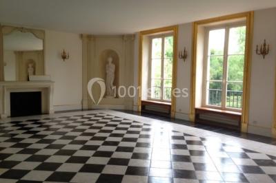 Trois cerfs dans une clairière, deux broutant l'herbe et un levant la tête près d'une forêt dense.