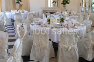 Trois cerfs dans une clairière, deux broutant l'herbe et un levant la tête près d'une forêt dense.
