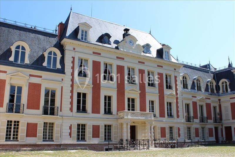 Façade d'un bâtiment historique en briques rouges et blanches avec des fenêtres à volets et un toit mansardé.