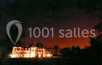 Trois cerfs dans une clairière, deux broutant l'herbe et un levant la tête près d'une forêt dense.