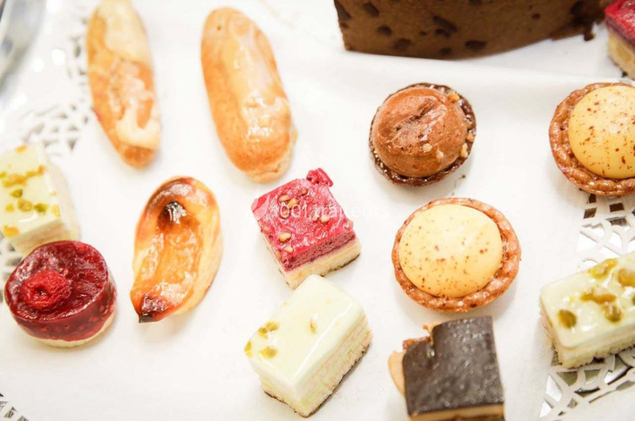Assortiment de petits desserts variés présentés sur un plateau blanc, incluant tartes, gâteaux et éclairs.