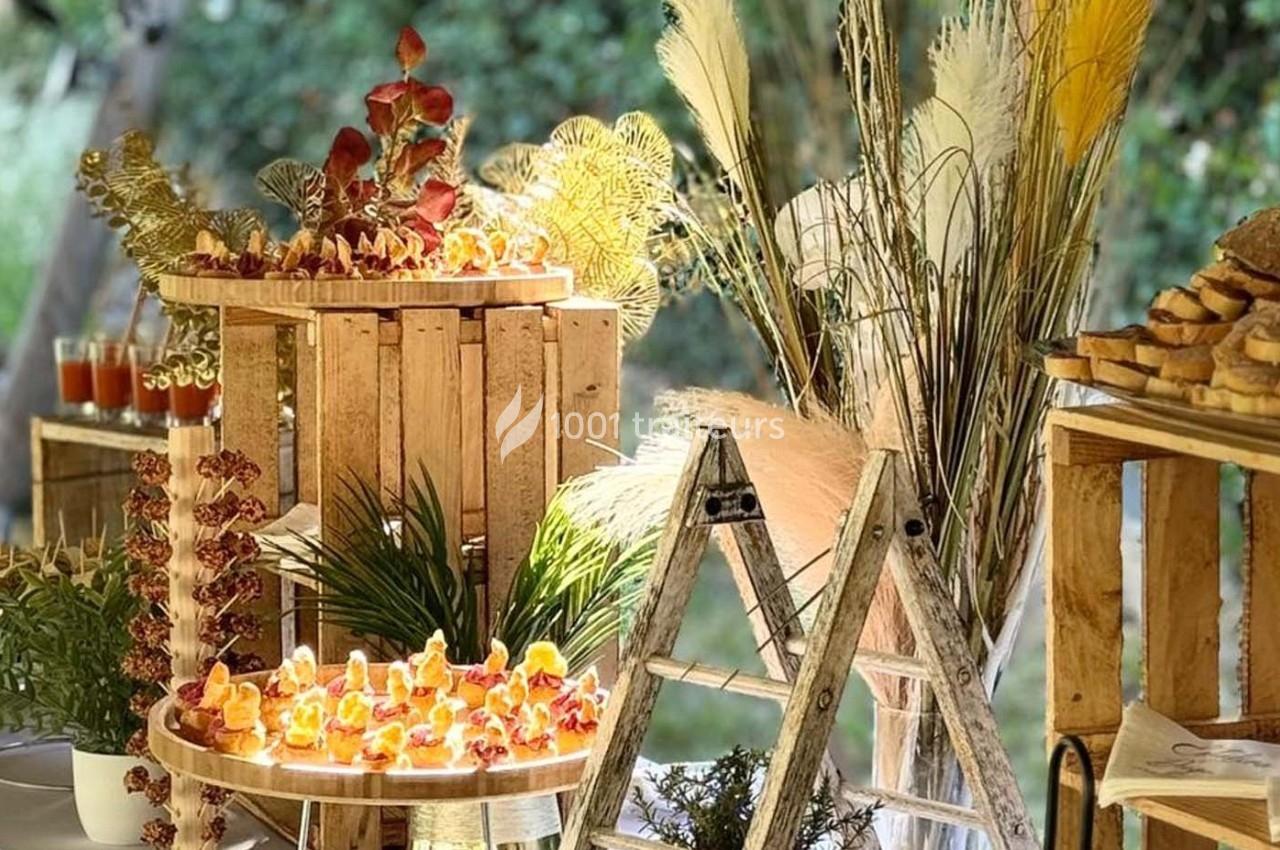 Buffet champêtre avec présentoirs en bois, amuse-bouches colorés et décorations végétales dans un cadre extérieur.