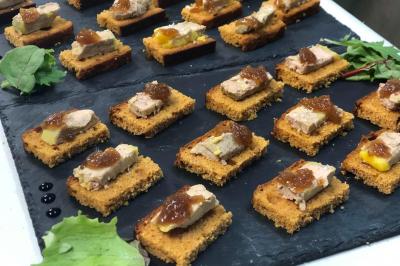 Buffet avec des amuse-bouches variés présentés sur des plateaux en bois et des verrines en arrière-plan.