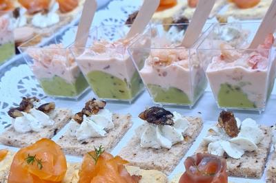 Buffet avec des amuse-bouches variés présentés sur des plateaux en bois et des verrines en arrière-plan.
