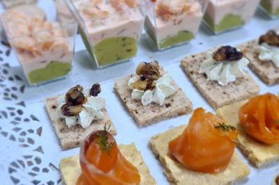 Buffet avec des amuse-bouches variés présentés sur des plateaux en bois et des verrines en arrière-plan.