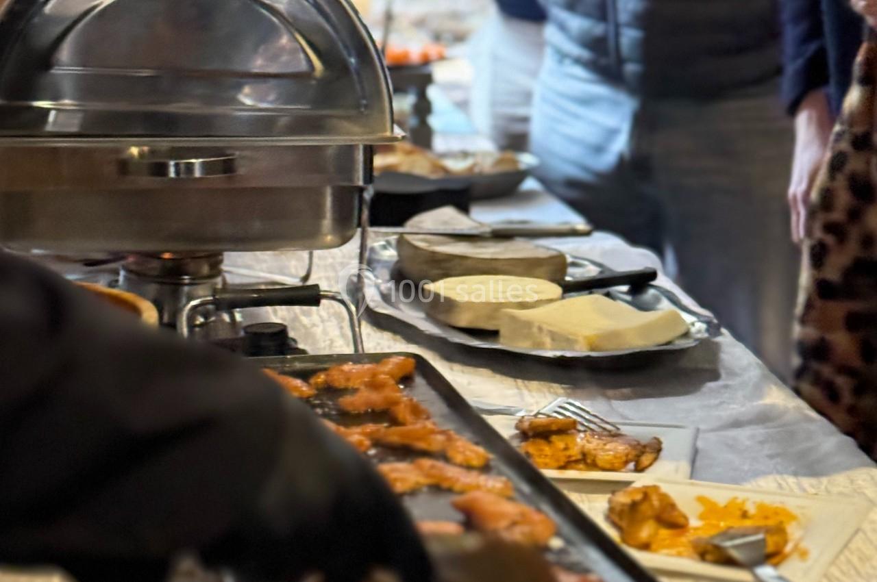 Buffet avec des plats chauds, des grillades et des convives se servant dans une ambiance conviviale.