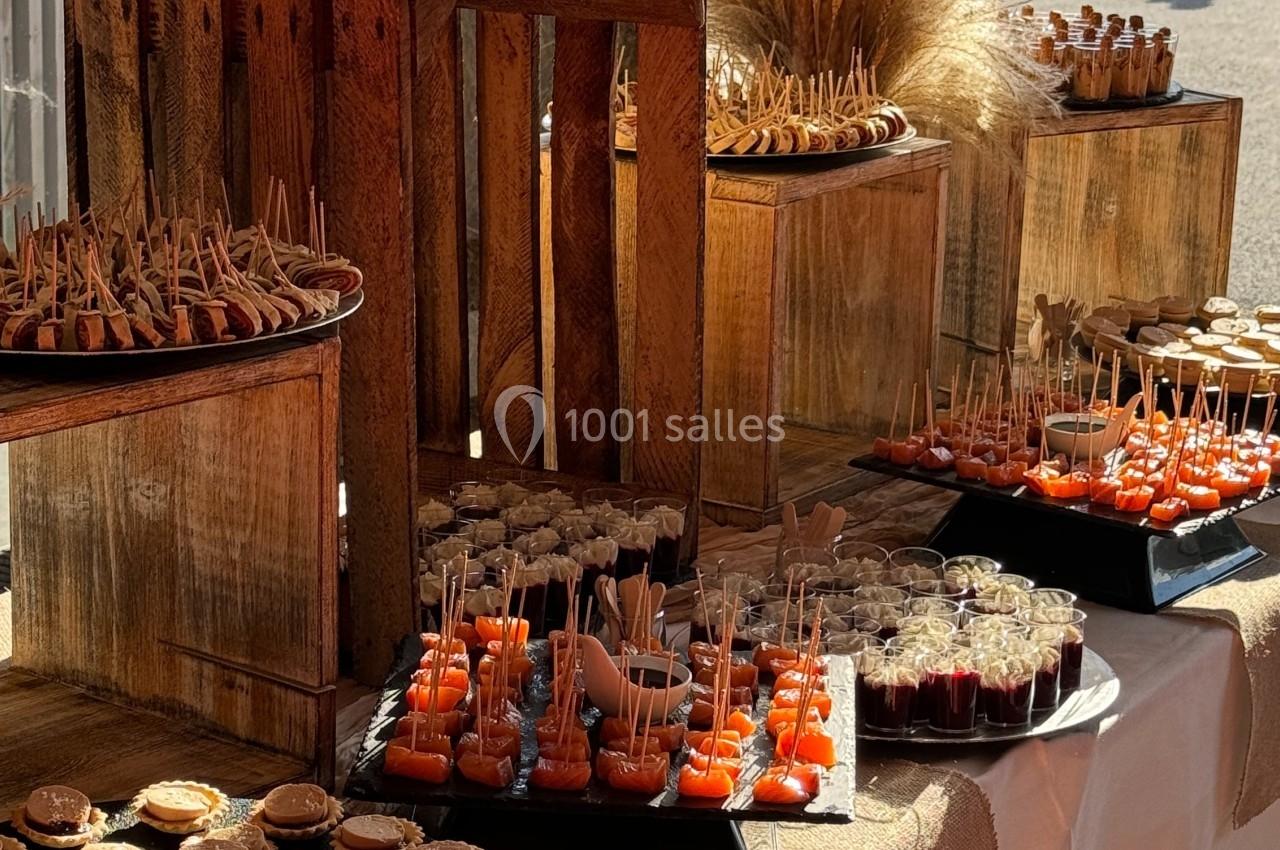 Buffet de réception avec assortiments de bouchées salées et sucrées présentés sur des plateaux et des caisses en bois.