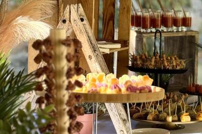 Buffet avec des amuse-bouches variés présentés sur des plateaux en bois et des verrines en arrière-plan.