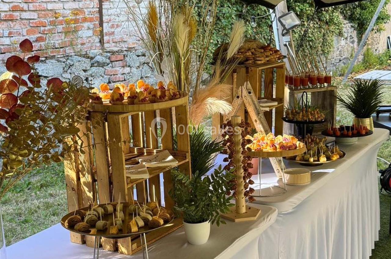 Buffet en extérieur avec présentation soignée de desserts et amuse-bouches sur des étagères en bois et une table blanche.