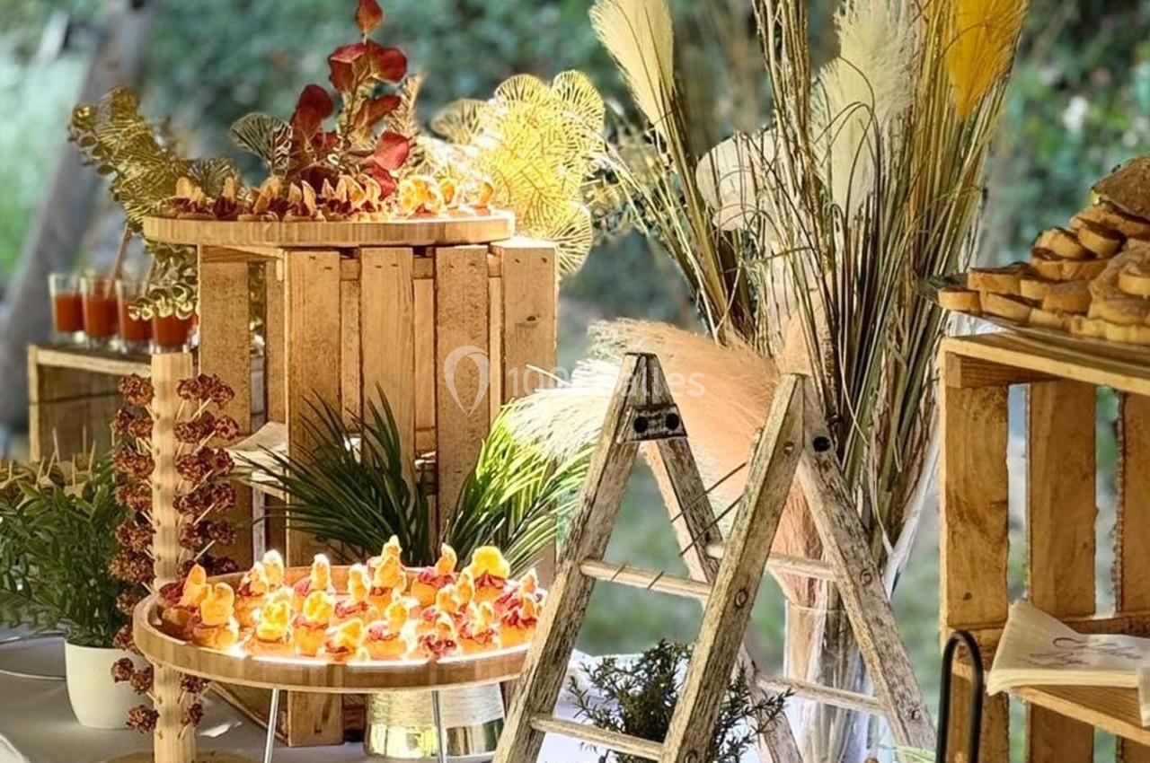 Buffet décoratif en extérieur avec des plateaux de nourriture, des caisses en bois et des éléments végétaux.