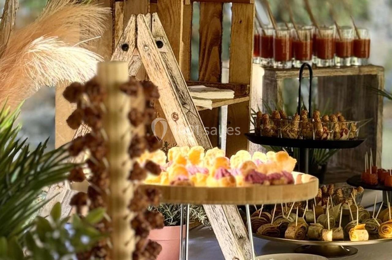 Buffet avec des amuse-bouches variés présentés sur des plateaux en bois et des verrines en arrière-plan.