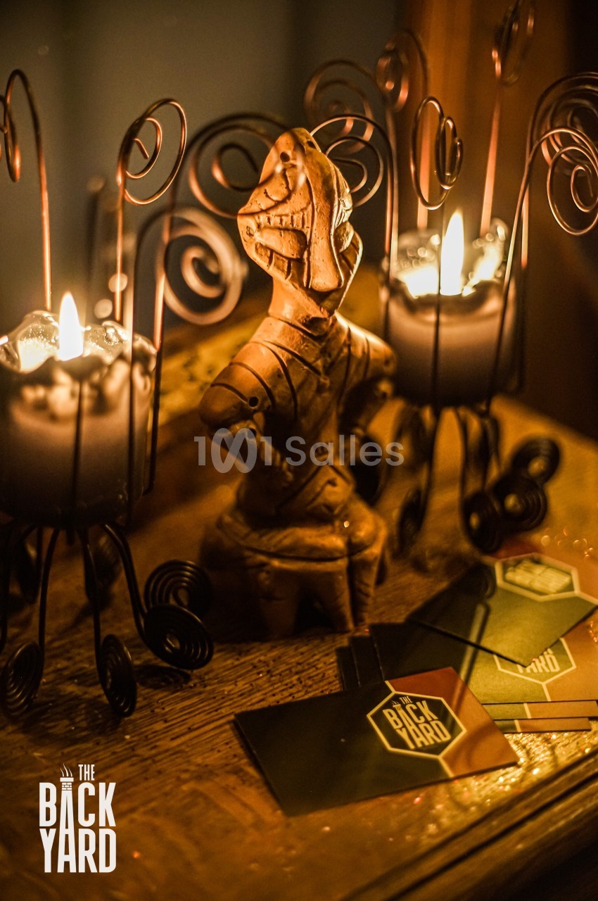 Statue en bois sculptée entourée de bougies allumées et de cartes posées sur une table en bois.