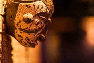 Deux statuettes africaines en gros plan, éclairées par des bougies en arrière-plan dans une ambiance tamisée.