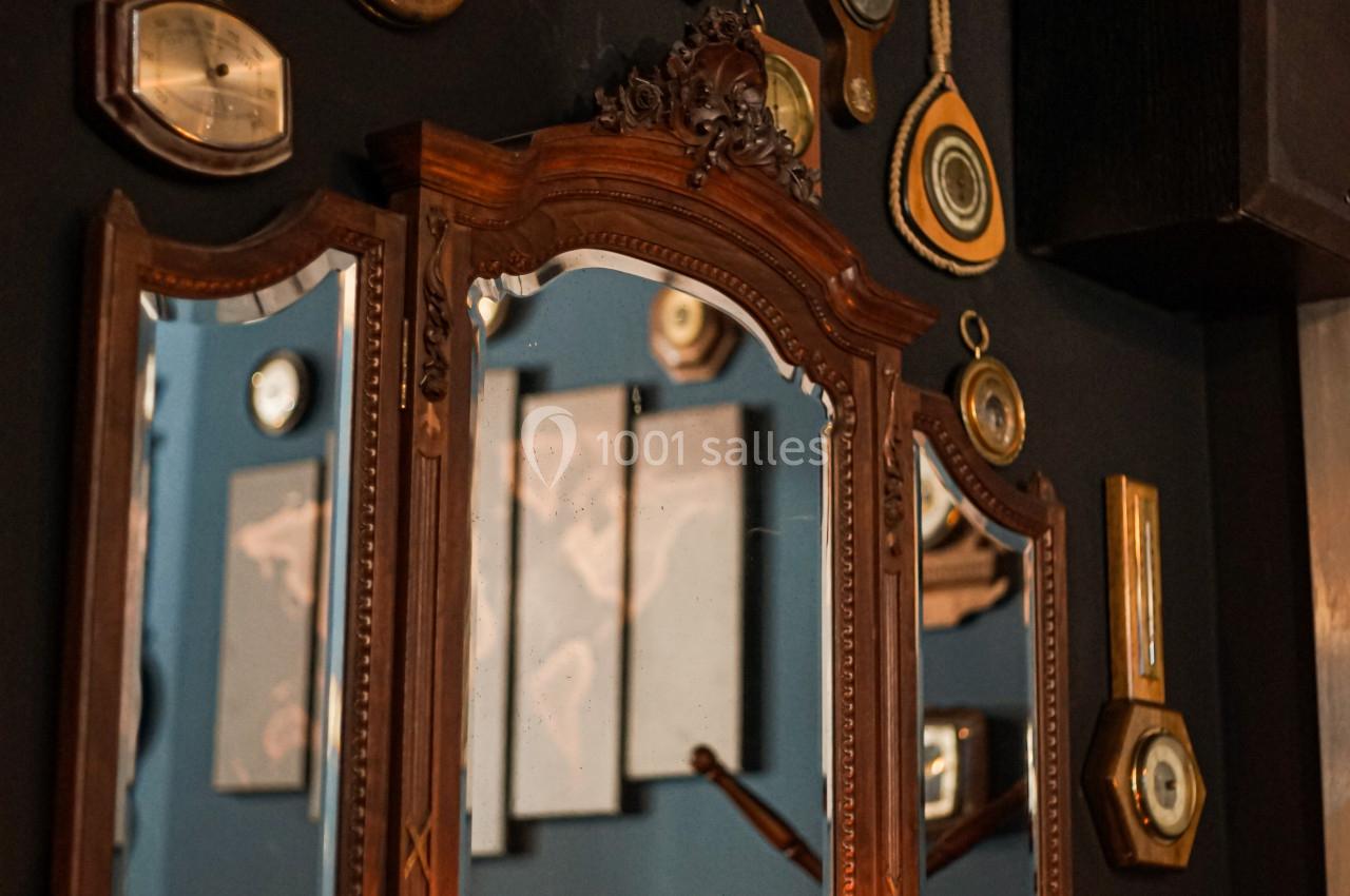 Miroir ancien entouré de décorations nautiques et d'objets vintage, avec des bougies allumées sur une étagère en bois.