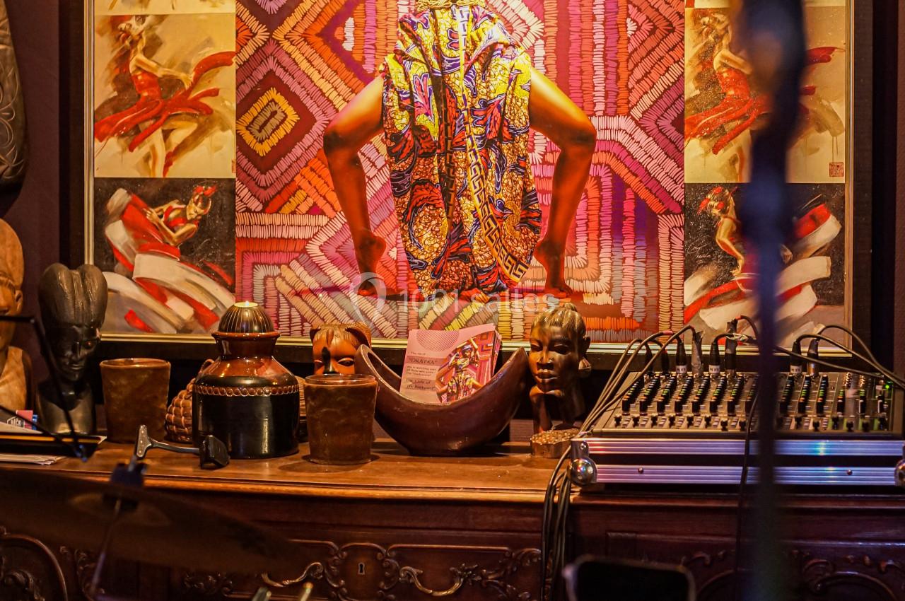 Une scène intérieure avec une batterie au premier plan et une œuvre d'art colorée représentant une danseuse en arrière-plan.